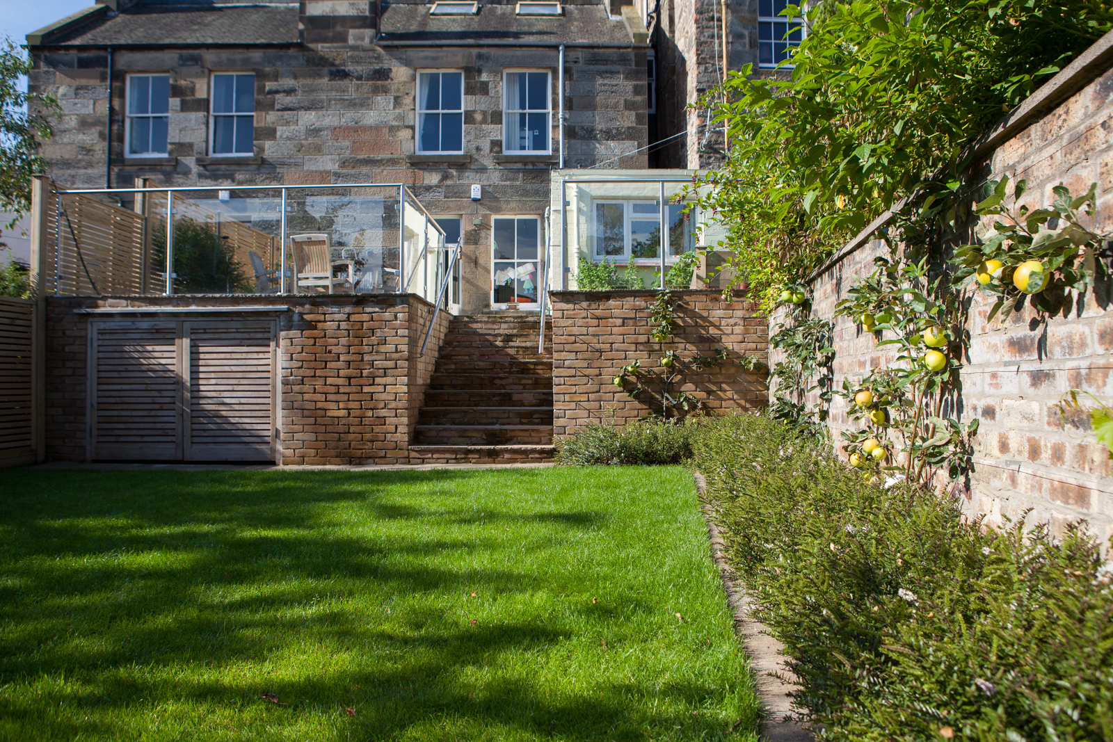 A family friendly garden with espalier fruit trees against a brick wall